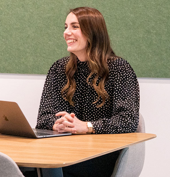 Grace sitting at her desk, smiling towards the distance.